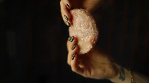 Hands gracefully holding a meat cutlet, showcasing its unique texture and color Vidéo 332847528