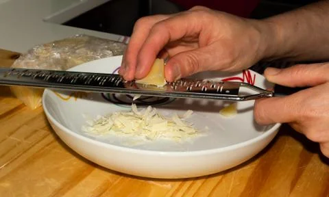 Hands grating cheese on a plate Stock Photos