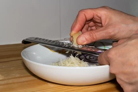 Hands grating cheese on a plate Stock Photos