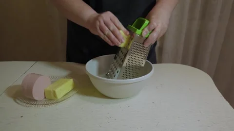 Hands grating cheese into white mixing bowl Stockbeeldmateriaal 342361700