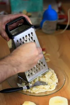 Hands grating a red apple onto a plate Stock Photos