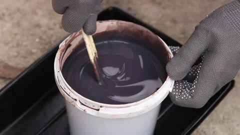 Hands in gray protective gloves stir dark varnish with wooden sticks Stock-Footage 334135928