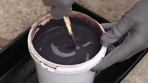 Hands in gray protective gloves stir dark varnish with wooden sticks Stock-Footage 334135929