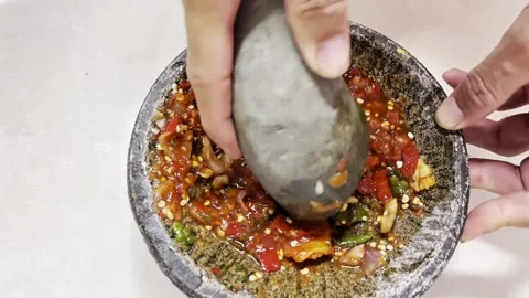 Hands grinding fresh ingredients to make Indonesian chili sauce Stock Footage 338395111