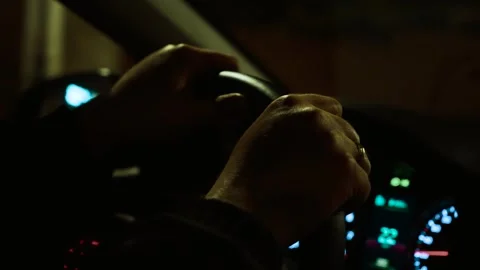 Hands gripping steering wheel while unrecognizable man driving through city Stock Footage 311818787
