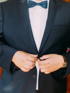 The hands of the groom are buttoning the wedding jacket. Stock Photos