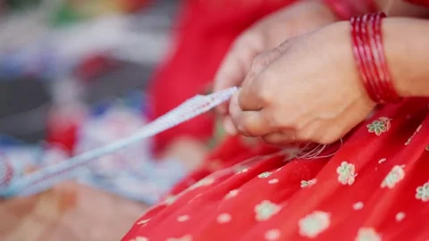 Hands guide bead string while seated in red sari in Nepal Stock Footage 342399382