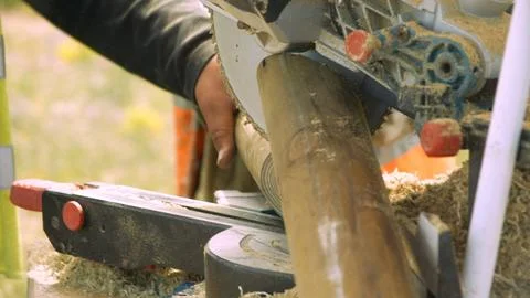 Hands guiding a chainsaw beside a log outdoors Stock Photos