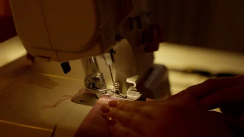 Hands Guiding Fabric Through Overlock Sewing Machine. Close-up of hands expertly Stock Footage 264388826