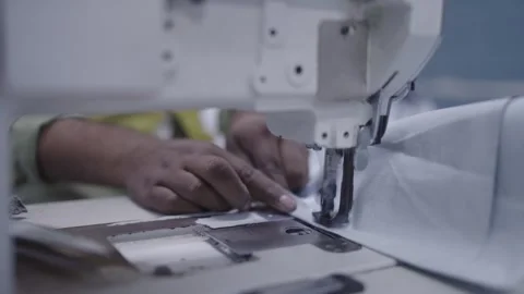 Hands guiding fabric through sewing machine in sailkot pakistan factory Stock Footage 317222568