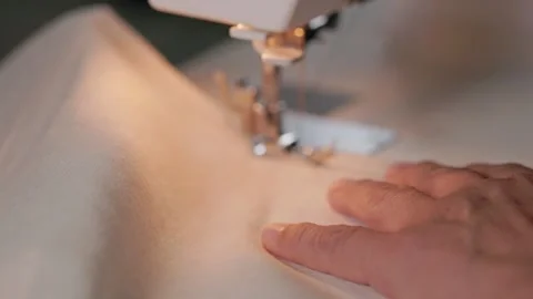 Hands guiding linen fabric while sewing at home Stock Footage 345456535