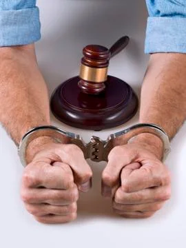 Hands handcuffed next to a gavel Stock Photos