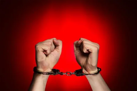 Hands with handcuffs on red background Stock Photos