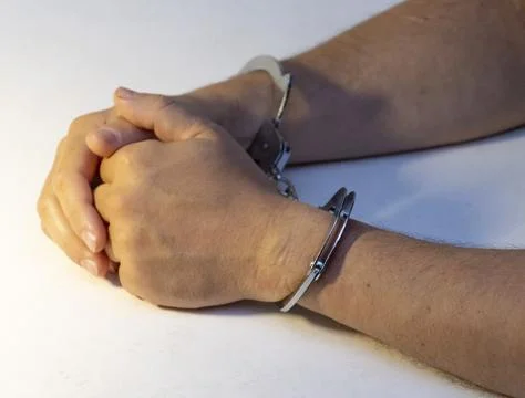 Hands in handcuffs on white table Foto stock