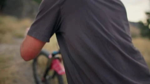 Hands on handlebars while pushing bike up mountain trail Stock Footage 212163938