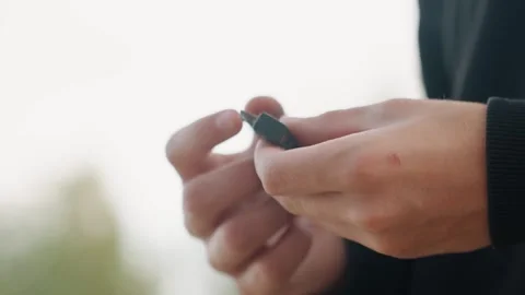 Hands handling device. Closeup of hands managing tiny black component outdoors Stock Footage 332364985