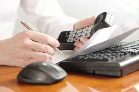 Hands with handset on a computer keyboard Stock Photos