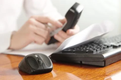 Hands with handset on a computer keyboard Stock Photos