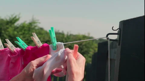 Hands hang pink and white clothes on a line Stock Footage 340531202
