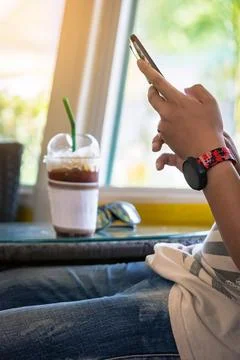 Hands of happy man using cell phone sitting on couch at home. View of man l.. Stock Photos