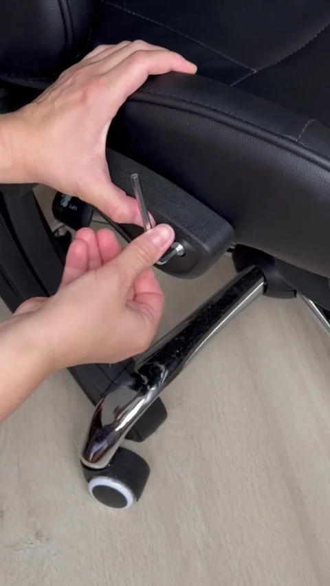 Hands with hex key disassembling the armrest of a black office chair indoors Stock Footage 316820558