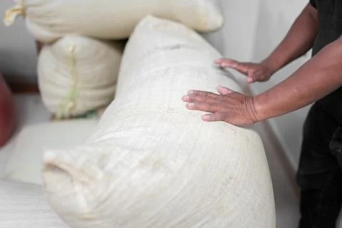 Hands of an Hispanic farmer stacking coffee sacks in the warehouse Stock Photos