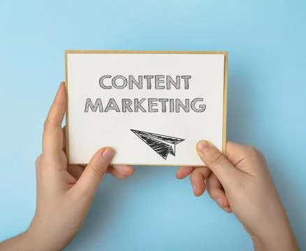 Hands hold card with text Content Marketing on light blue Stock Photos