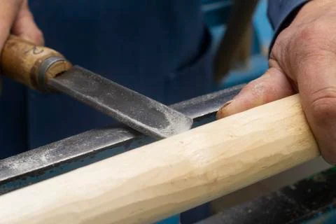 Hands hold a chisel for processing on the turning machine of a wooden bar Stock Photos