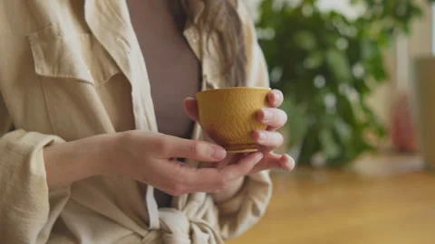 Hands hold a cup of tea during a tea ceremony indoors in daylight 스톡 동영상 348196947