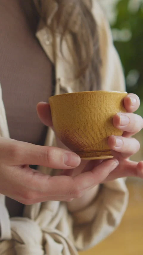 Hands hold a cup of tea during a tea ceremony indoors in daylight 스톡 동영상 348325320