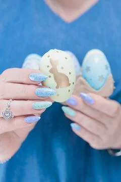 Hands hold Easter eggs. Light yellow, blue and pink color. Stock Photos