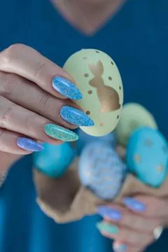 Hands hold Easter eggs. Light yellow, blue and pink color. Stock Photos