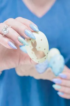 Hands hold Easter eggs. Light yellow, blue and pink color. Stock Photos