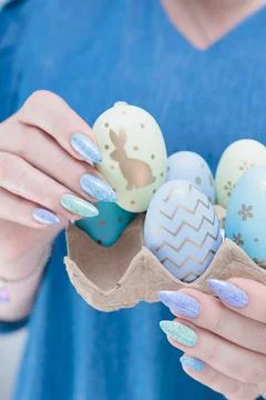 Hands hold Easter eggs. Light yellow, blue and pink color. Stock Photos