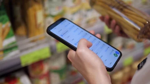 Hands hold eco-friendly breadsticks and a phone with a partially checked Stock Footage 315744502