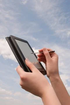 Hands hold electronic book reader against blue sky Hands hold electronic b... Foto stock