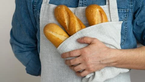 Hands hold freshly baked bread in towel. French baguette. Bakery. Food Stock Photos