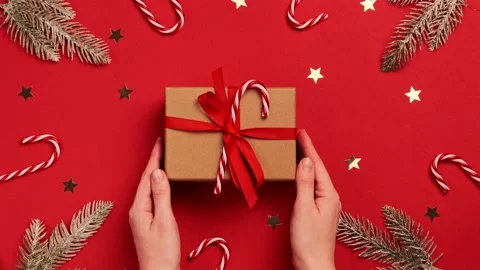 Hands hold gift box with a bow on red background of Christmas Stock Footage 144137669