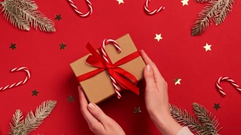 Hands hold a gift box with a bow on the red background of Christmas Stock Footage 144137877