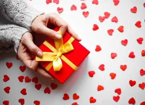 Hands hold a gift on a white background with red hearts Stock Photos