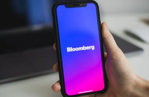 Hands hold the iPhone with Bloomberg app logo on the screen. Stock Photos