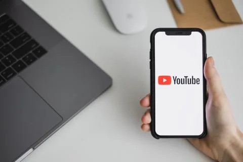 Hands hold the iPhone with Youtube app logo on the screen. Stock Photos