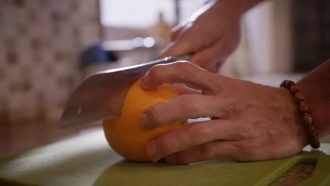 Hands hold large orange while slicing in half on cutting board Stock Footage 123737623