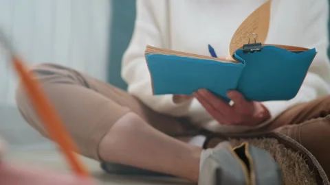 Hands hold notebook. Individual studying grammar notes comfortably at home Stock Footage 345517553