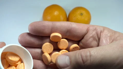 Hands hold orange vitamins next to orange fruits in 4K Stock Footage 146679286