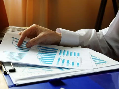 Hands hold papers with graphs about the financial results of the company. Stock Photos