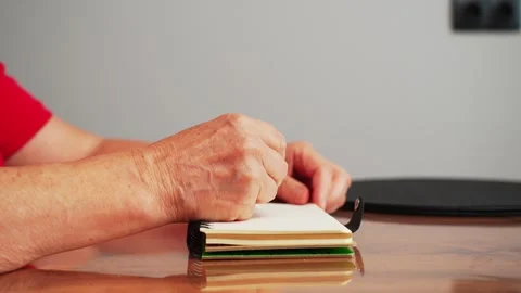 Hands hold pencil and prepare to draw on blank notebook on wooden table in indoo Stock Footage 330073059