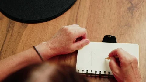 Hands hold pencil and prepare to draw on blank notebook on wooden table in indoo Stock Footage 330889592