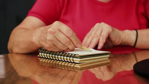 Hands hold pencil and prepare to draw on blank notebook on wooden table in indoo Stock Footage 330889688