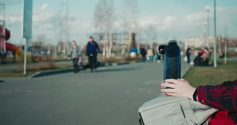 Hands hold plastic reusable water bottle against blurry background of outdoors Stock Footage 197593044